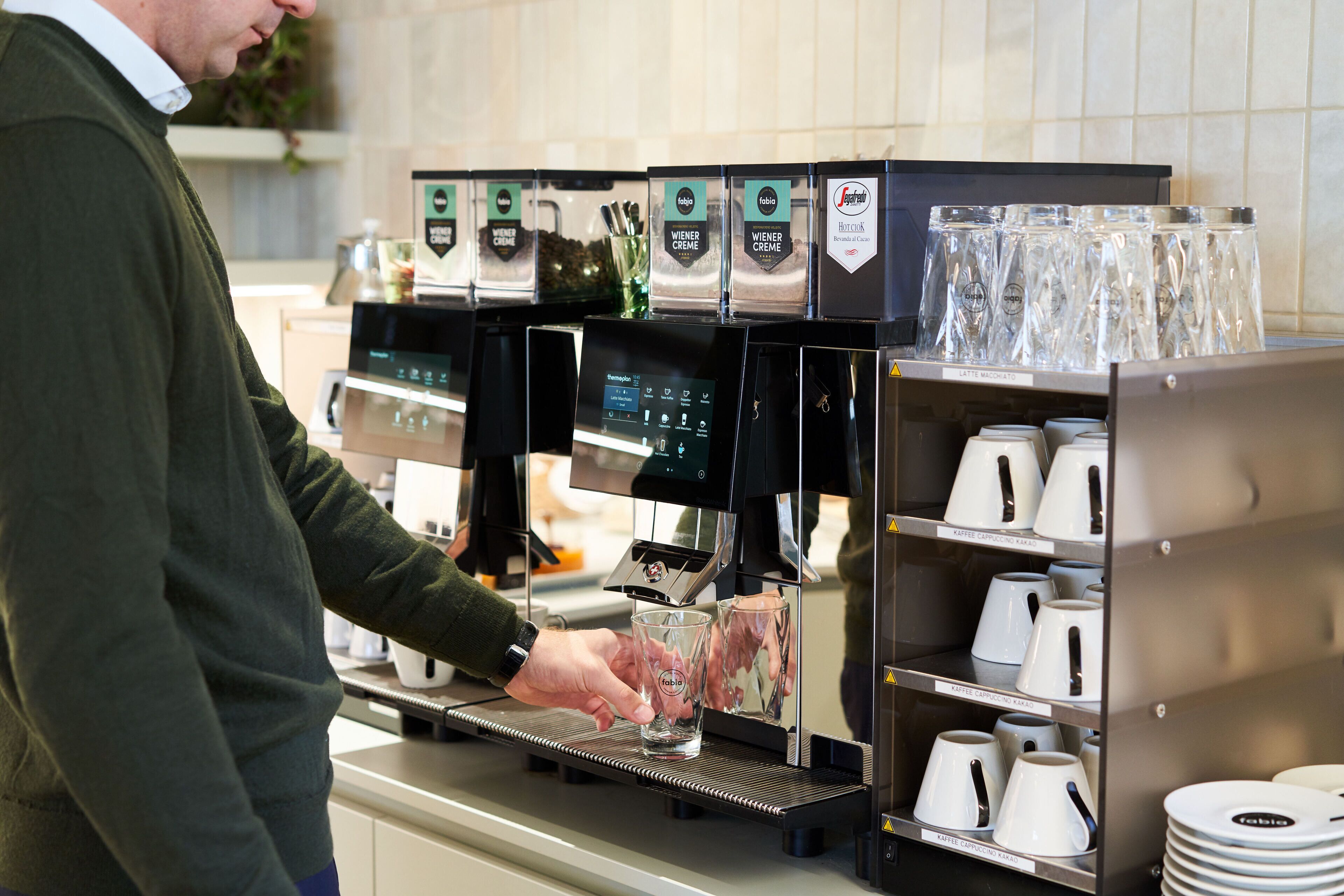 A coffee machine with multiple brewing options and a selection of cups and saucers.