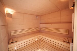 Una sauna con bancos de madera y un calentador fijado a la pared.