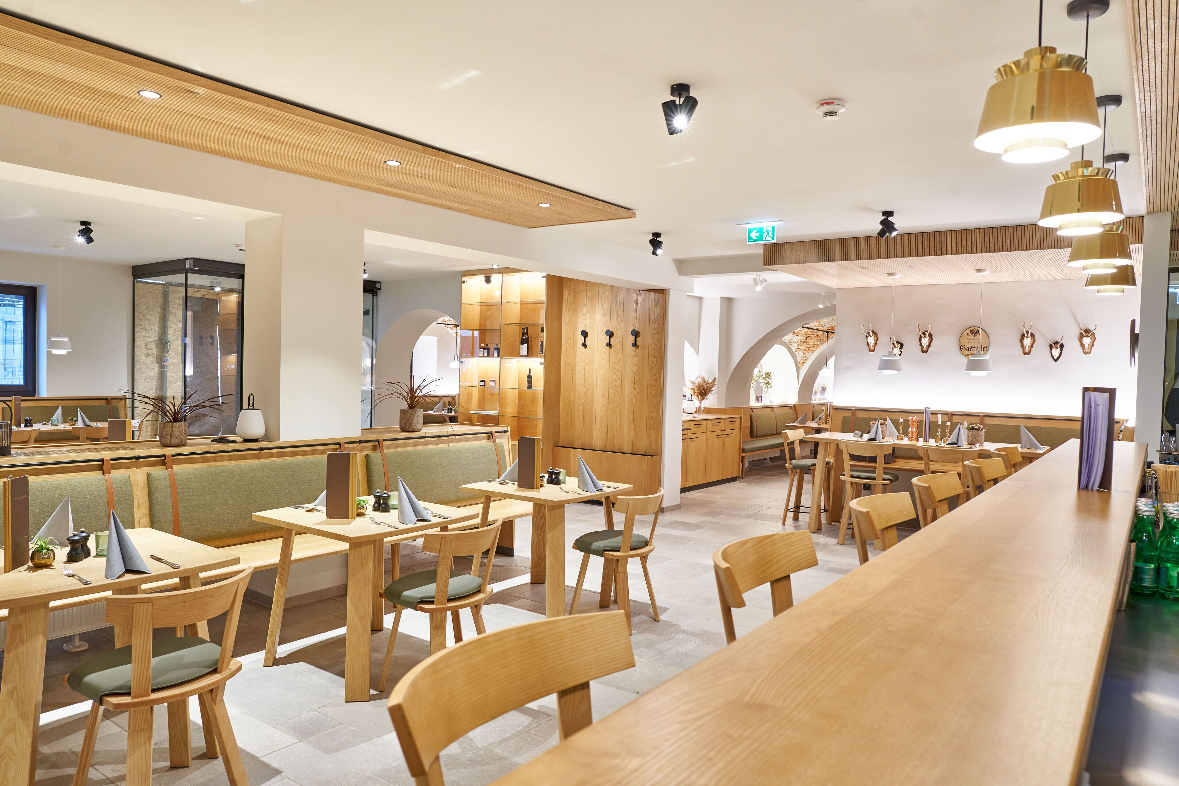 A modern restaurant with wooden furniture, a long counter, and a variety of wall decorations.