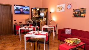 Zona de menjador amb televisió, cuina i un sofà vermell.