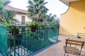 A balcony with a metal railing, a wooden bench, and potted plants.