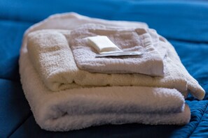 A stack of folded towels on a blue bedspread.