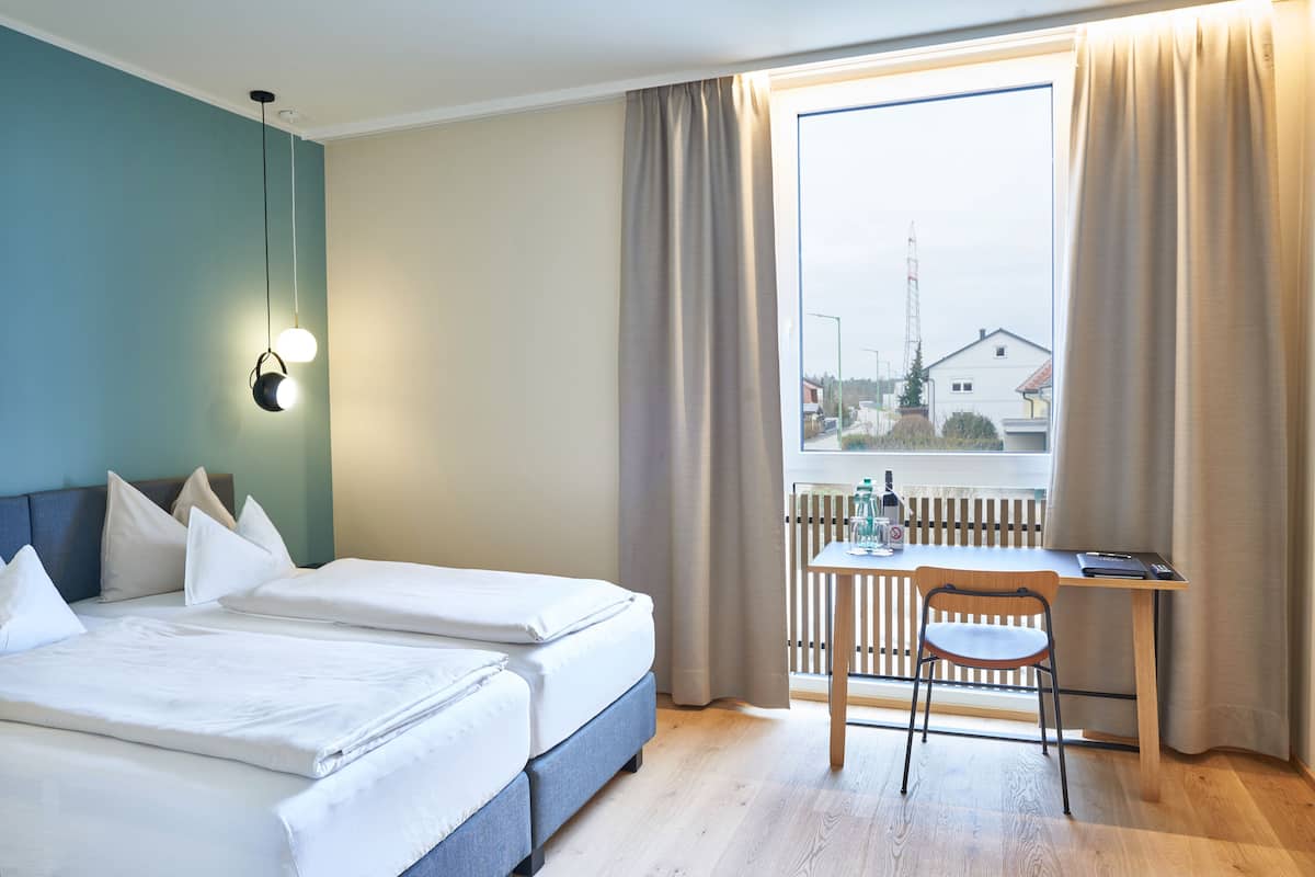 A hotel room with two beds, a desk, and a chair.