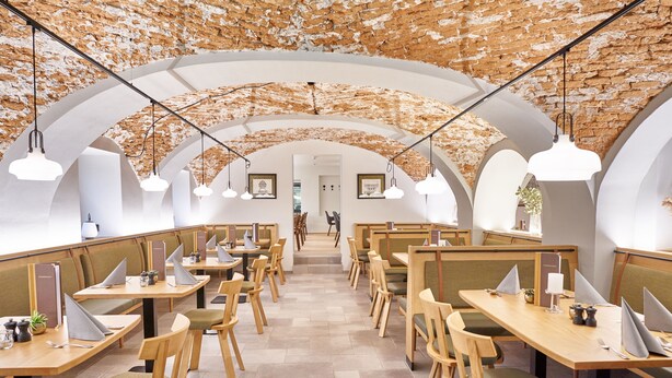 A modern dining area with high arched ceilings and wooden tables and chairs. - Gasthof Maxlhaid (Wels)