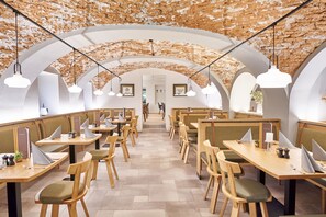 A modern dining area with high arched ceilings and wooden tables and chairs.