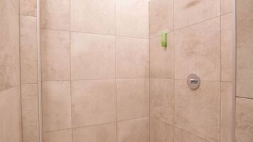 Un baño pequeño revestido de azulejos, con mampara de vidrio y ducha.