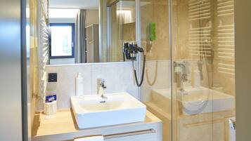 Une salle de bain moderne avec une douche à parois de verre, un lavabo blanc et un miroir au-dessus du lavabo.