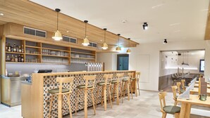 A modern bar area with a long counter, multiple bar stools, and shelves stocked with bottles and glasses. - Gasthof Maxlhaid (Wels)