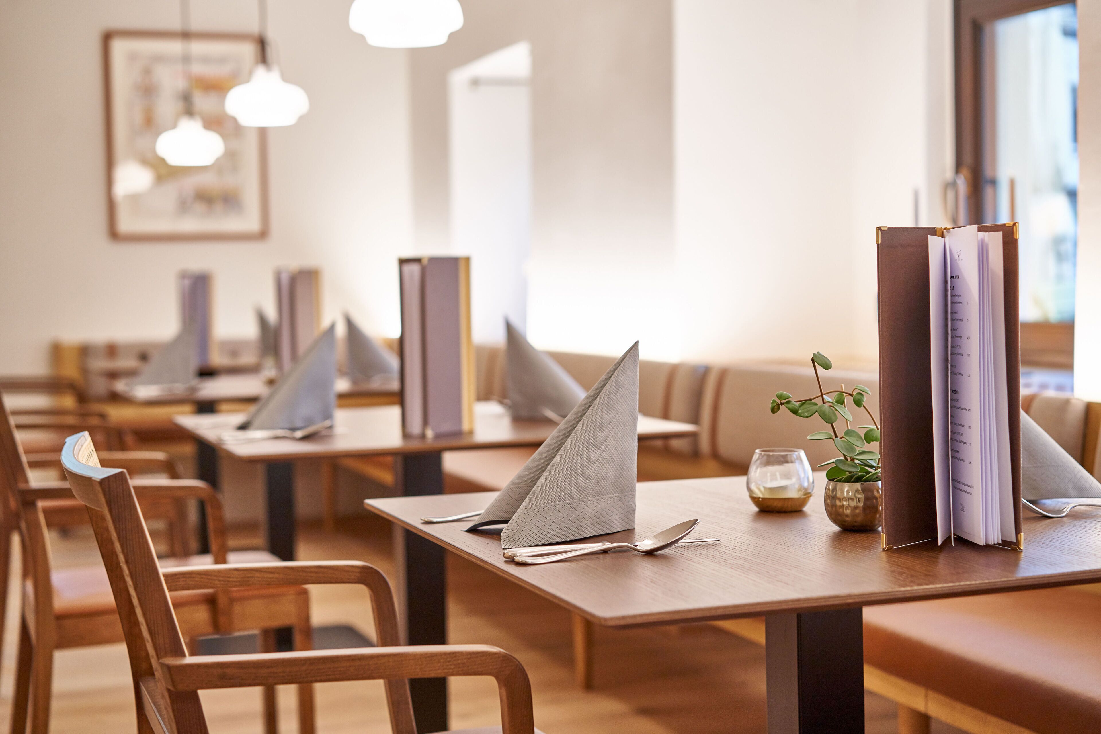 A restaurant with wooden tables, neatly arranged chairs, and a menu stand.