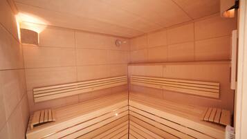 Una sauna con bancos de madera y un calentador fijado a la pared.