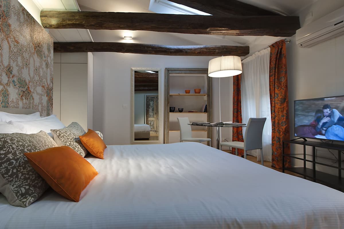 Une chambre d’hôtel avec un grand lit, une télévision, un bureau avec une chaise et une vue sur la salle de bain.