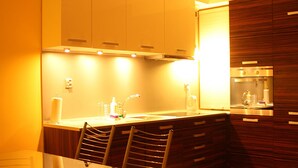 A modern kitchen with a dining area, featuring a table and chairs, a built-in oven, and a sink. - Jm Apartamenty (Szczecin)
