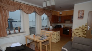 A compact living space with a dining area, kitchenette, and a view of the outside. - Jm Apartamenty (Szczecin)