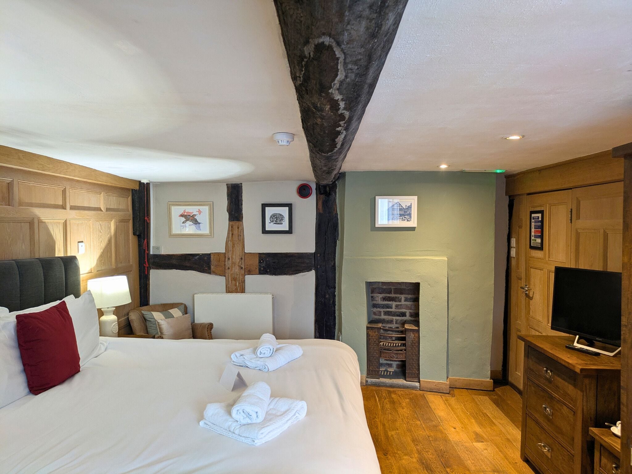 Een hotelkamer met een groot bed, een open haard, houten lambrisering en een televisie.