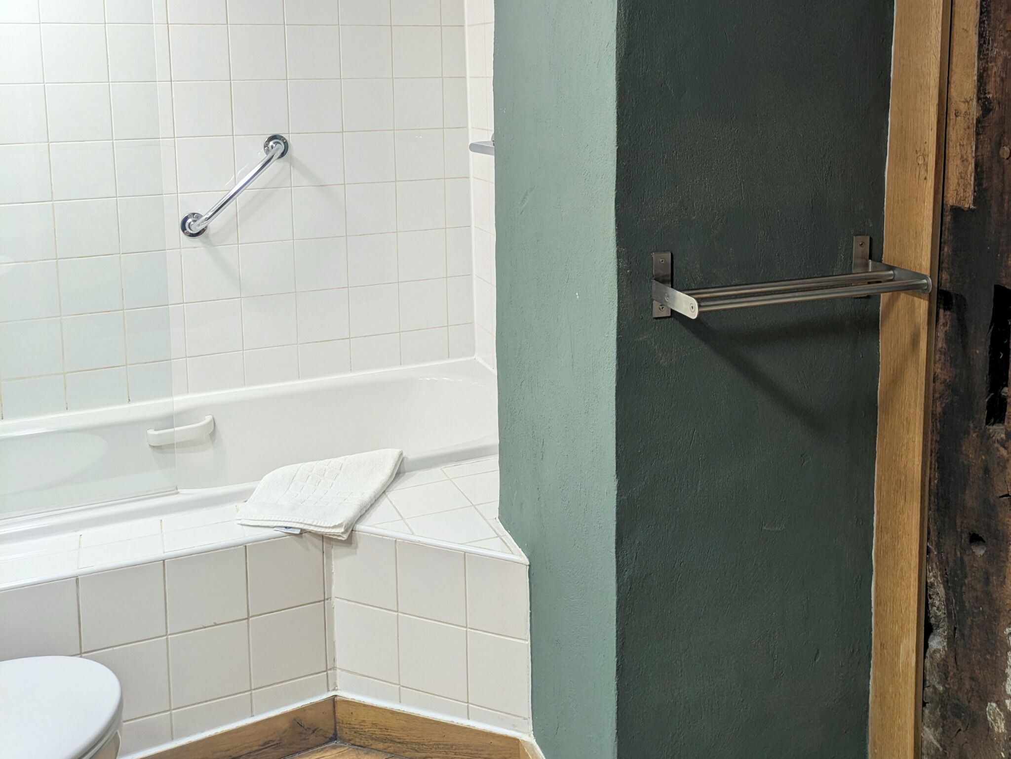 Ein Badezimmer mit einer weißen Badewanne, einer weißen Toilette und einer grünen Tür.