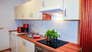 A kitchen with white cabinets, a stainless steel sink, a coffee maker, and a stove.