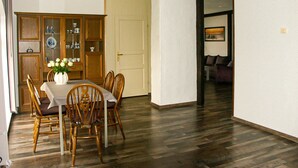A dining area with a wooden table and chairs, a cabinet with glass doors, and a door leading to another room.