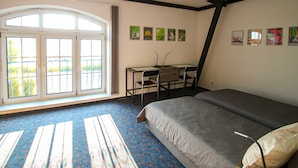 A bedroom with a bed, a desk, and a large window.