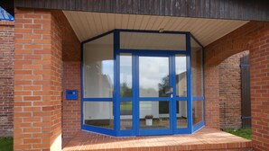 A building entrance with a glass door and brick walls.