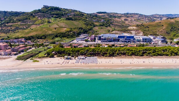 A coastal resort with a beach, hotel buildings, and a hilly backdrop. - Onda Hotel (Silvi)