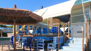 A beachside restaurant with outdoor seating, a thatched umbrella, and a staircase leading to the entrance. - Onda Hotel (Silvi)
