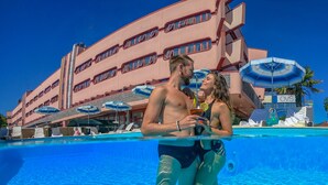A hotel with a pool area, multiple umbrellas, and a large building with balconies. - Onda Hotel (Silvi)