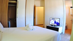 A hotel room with a bed, a TV, a wardrobe, and a bathroom. - Apartamento Serra - Gramado (Gramado)