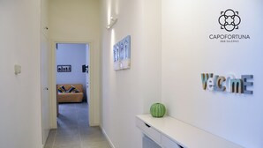 A hotel corridor with a reception desk, a green decorative object, and a wall-mounted sign. - Capofortuna B&B (Salerno)