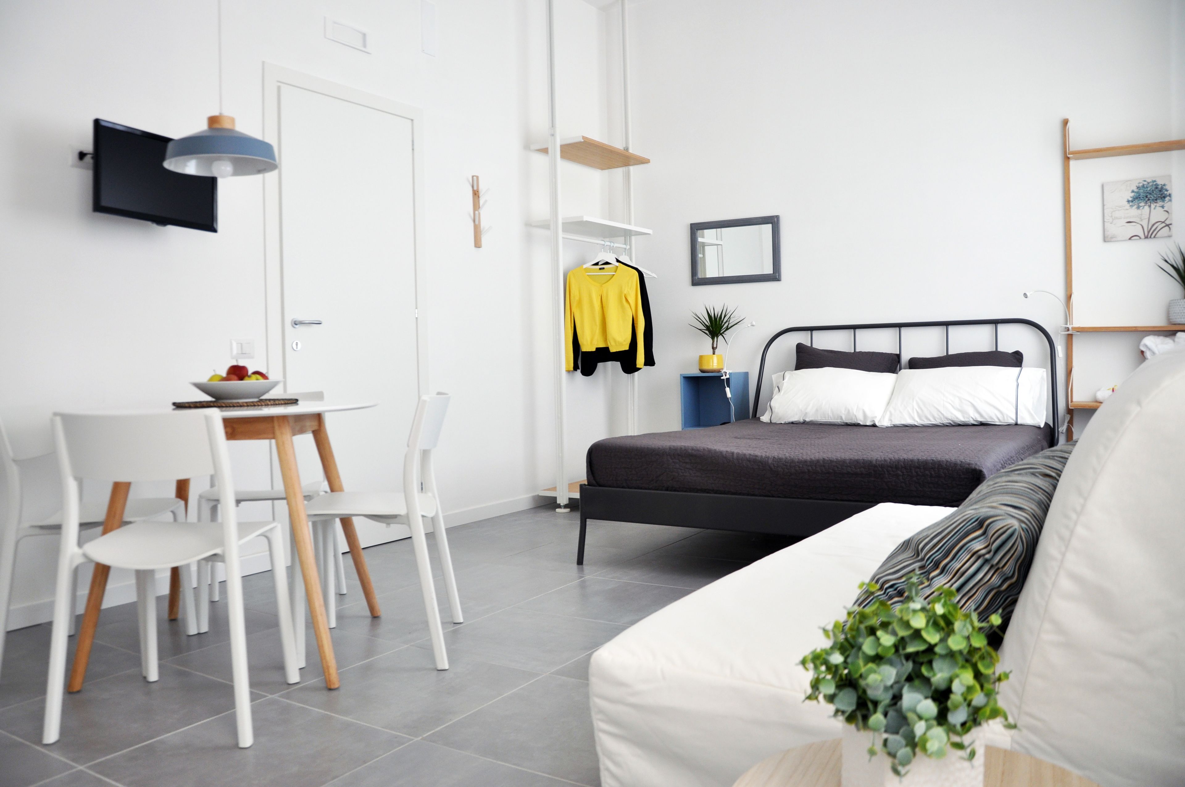 A modern bedroom with a bed, bedside table, and a small desk area with chairs.