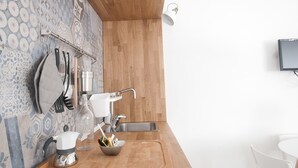 A modern kitchen with a wooden countertop, a black induction cooktop, and a tiled backsplash. - Capofortuna B&B (Salerno)