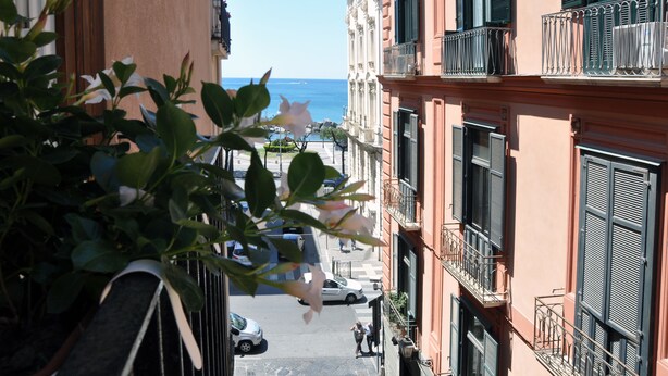 A narrow street with buildings on both sides, a clear view of the sea, and a few parked cars. - Capofortuna B&B (Salerno)