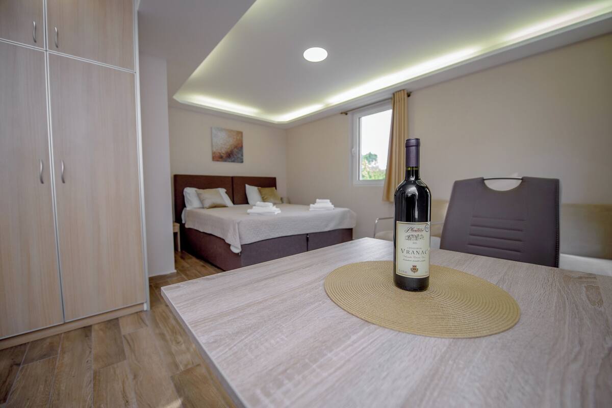 Une chambre d’hôtel avec un lit, une table sur laquelle se trouve une bouteille de vin et une armoire.