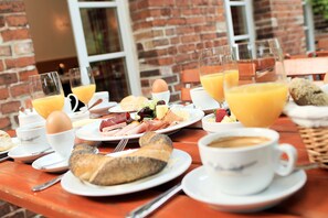 Una mesa de desayuno con platos de comida, vasos de jugo de naranja y una taza de café.