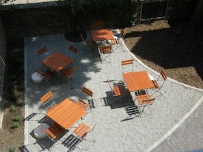 Un patio al aire libre con varias mesas y sillas de madera dispuestas sobre un suelo de grava.