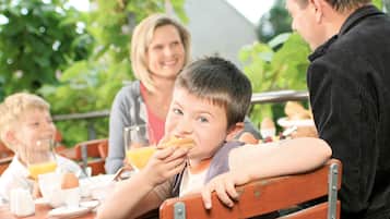 A family dining outdoors with a wooden table and chairs.