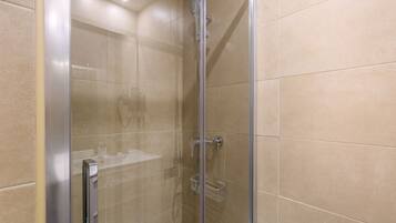 A glass-enclosed shower with a handheld showerhead and a towel rack.