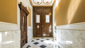 A hallway with a checkered floor, wooden doors, and marble walls.