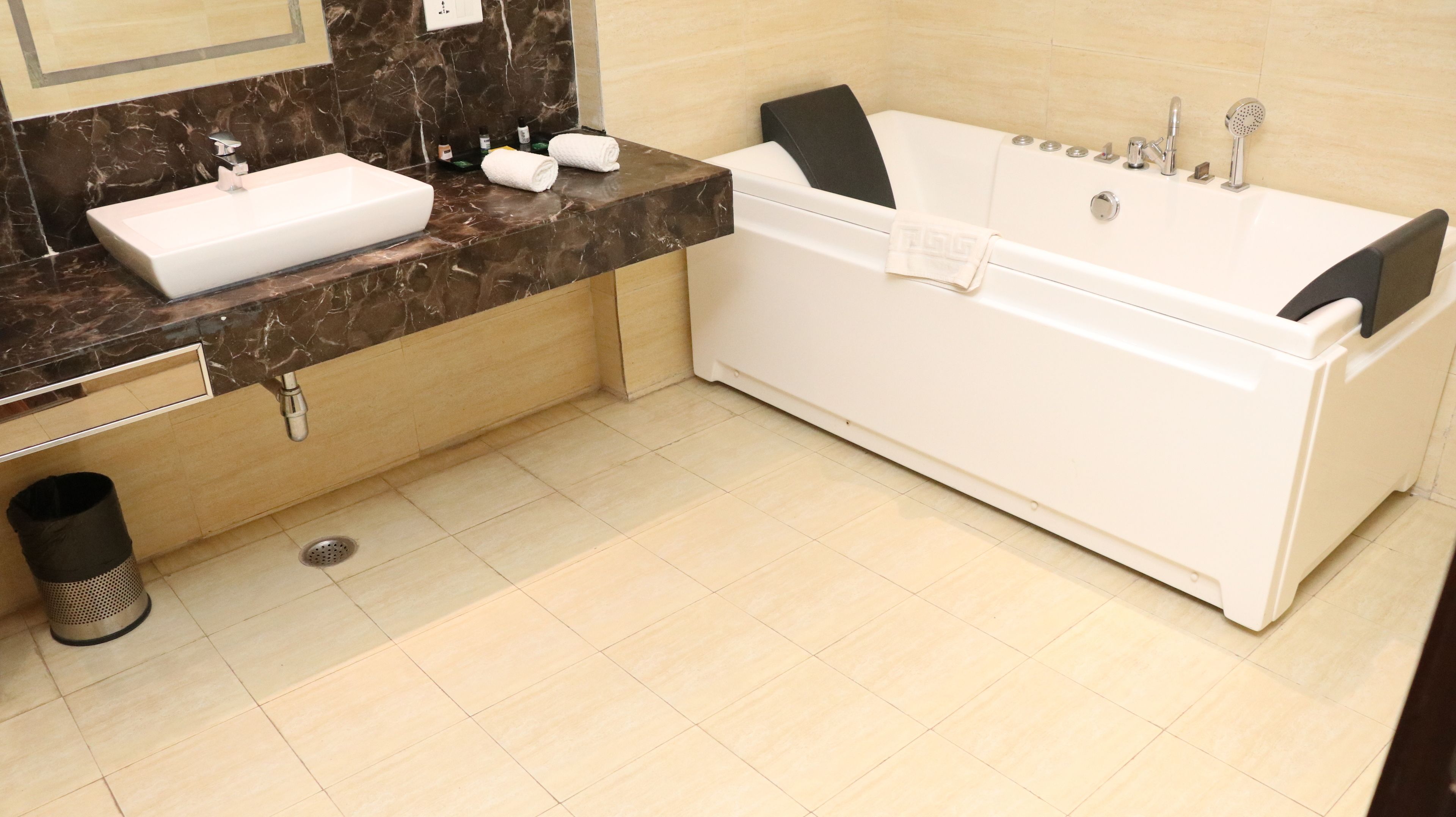 Un baño moderno con lavamanos blanco, bañera y encimera de mármol.