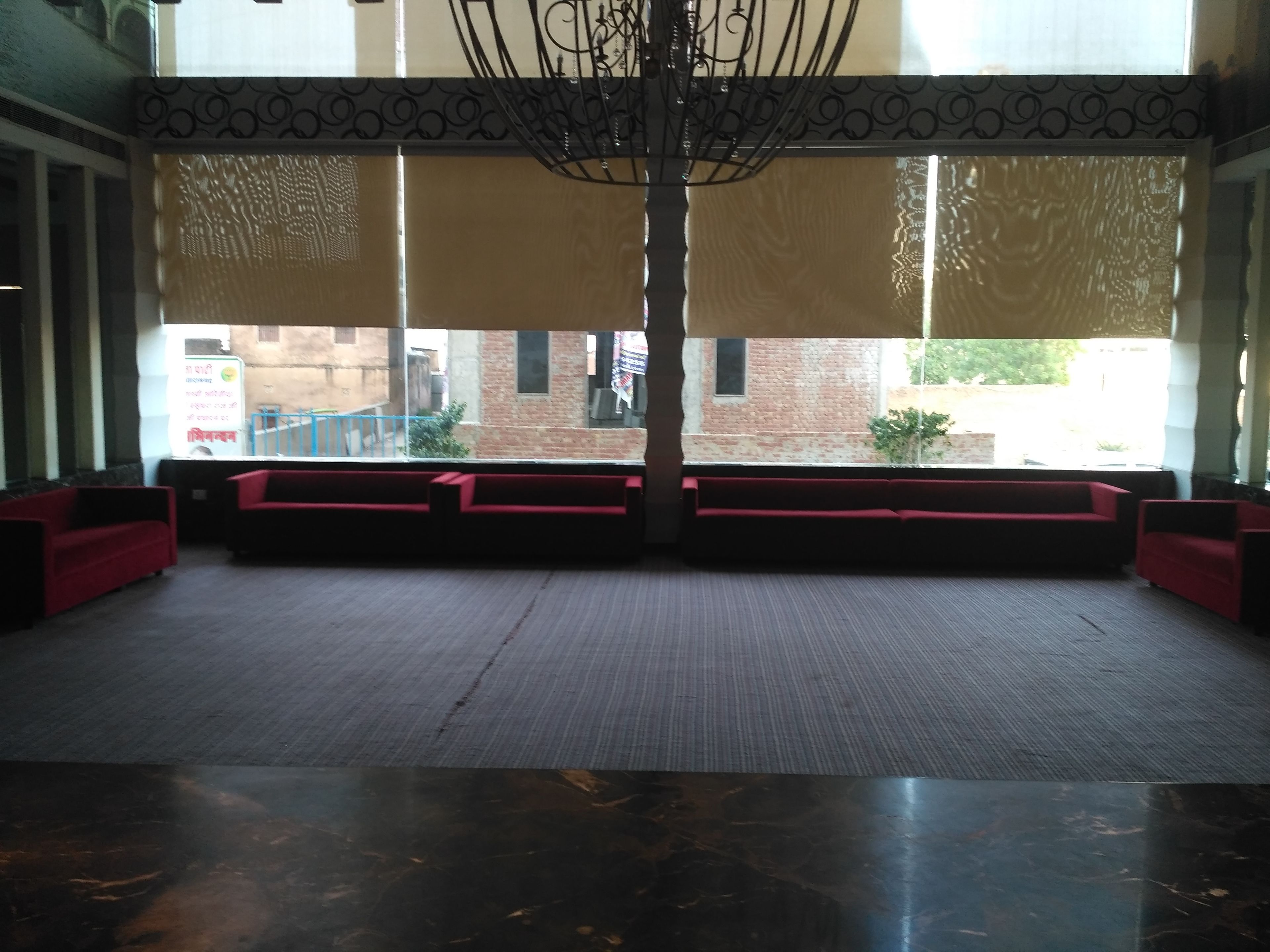 A spacious lobby with a high ceiling, a chandelier, and a large window offering a view of the outside.