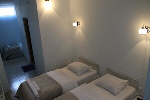 A hotel room with two single beds, a small table with a towel, and a window with curtains. - Hotel Lim (Batumi)