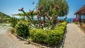 Ein Gartenweg, der zu einem Gebäude mit Meerblick führt.