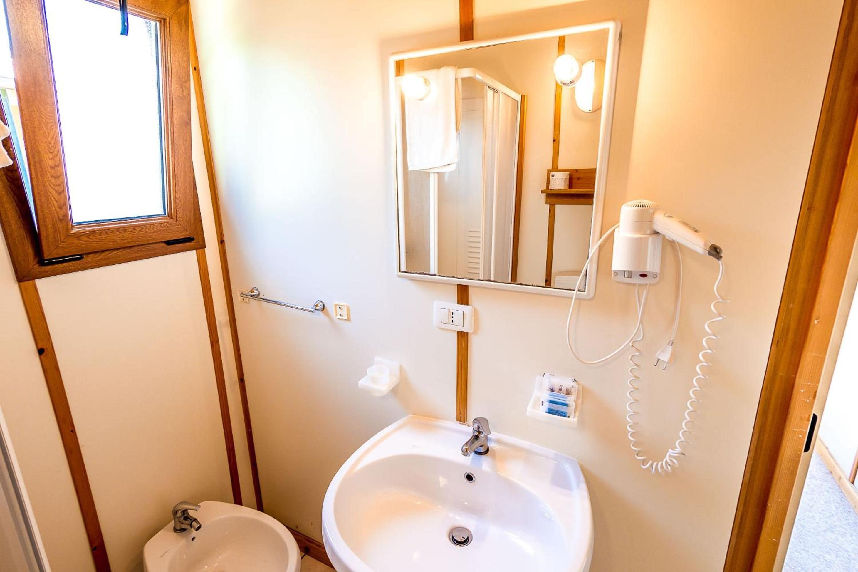 A bathroom with a sink, mirror, towel rack, and a hairdryer on the wall.