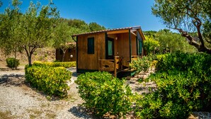 Eine Holzhütte mit Veranda, umgeben von dichtem Grün und Bäumen.
