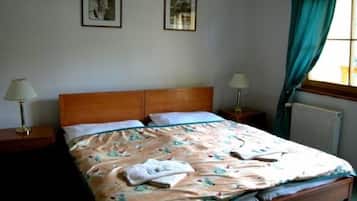 Un dormitorio con una cama de madera, dos mesitas de noche con lámparas y dos cuadros en la pared.