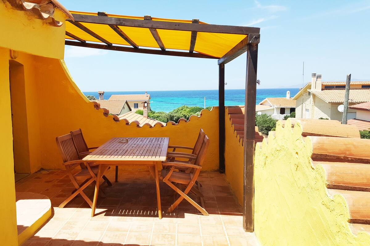Een terras met een tafel en stoelen, met uitzicht op de kust.