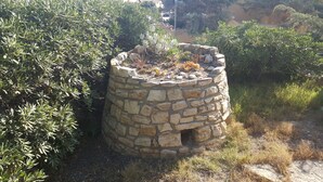 A stone structure surrounded by greenery. - La Baia Apartments (San Vero Milis)