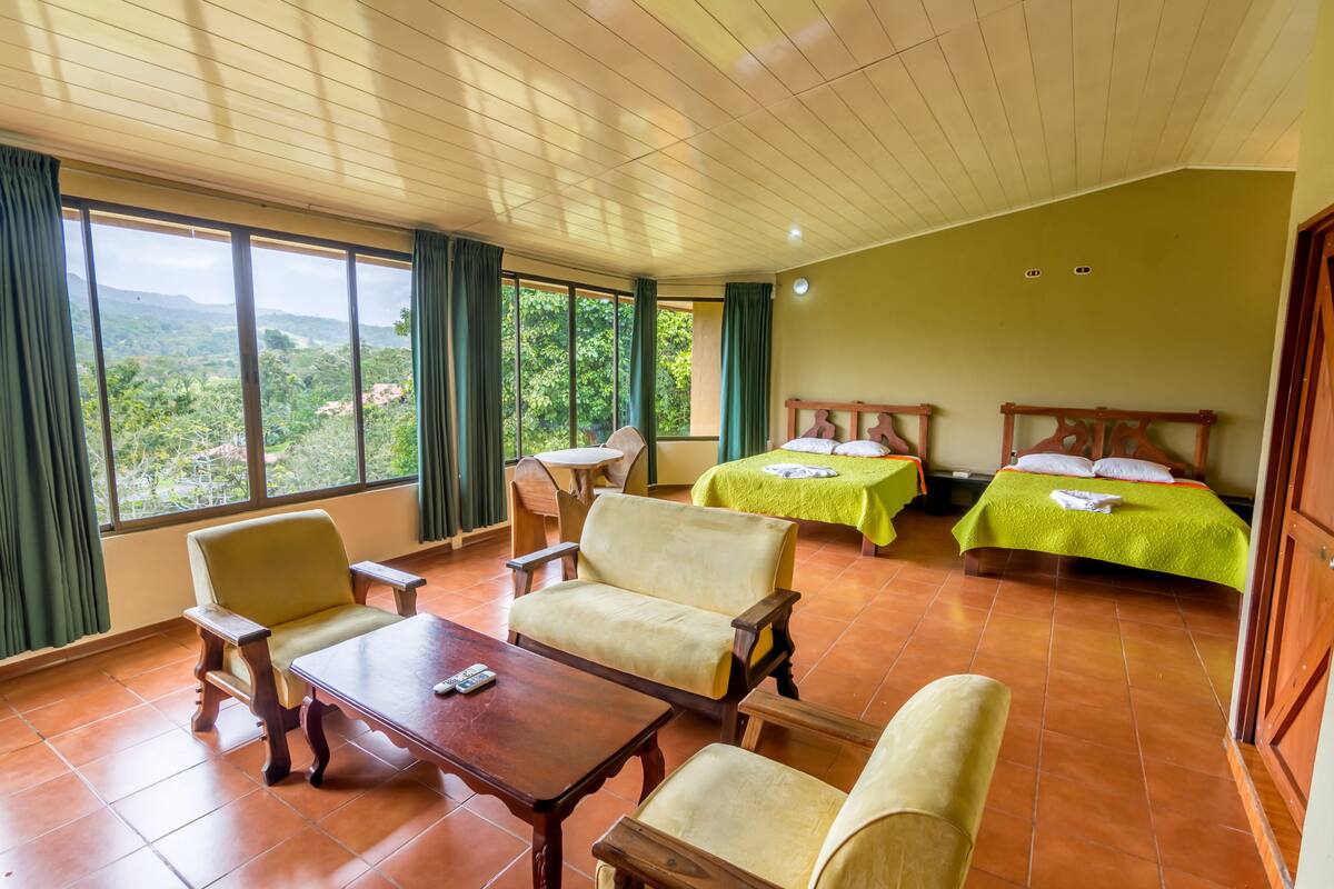 A room with two beds, a sofa, a table, and a chair.