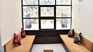 Una habitación con un ventanal grande, un ventilador de techo y un sofá con cojines estampados.