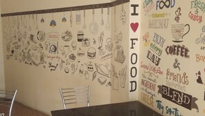 Una pared con diversas ilustraciones y texto relacionados con la comida, incluyendo 'I LOVE FOOD' y 'Prueba algo de queso'.