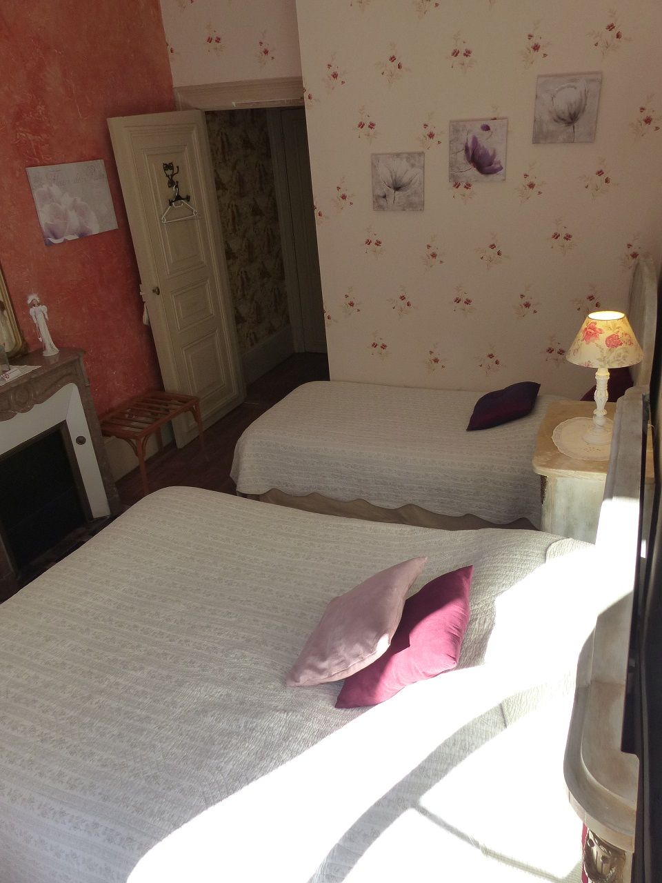 Een kamer met twee bedden, een tafeltje met een lamp en een deur.
